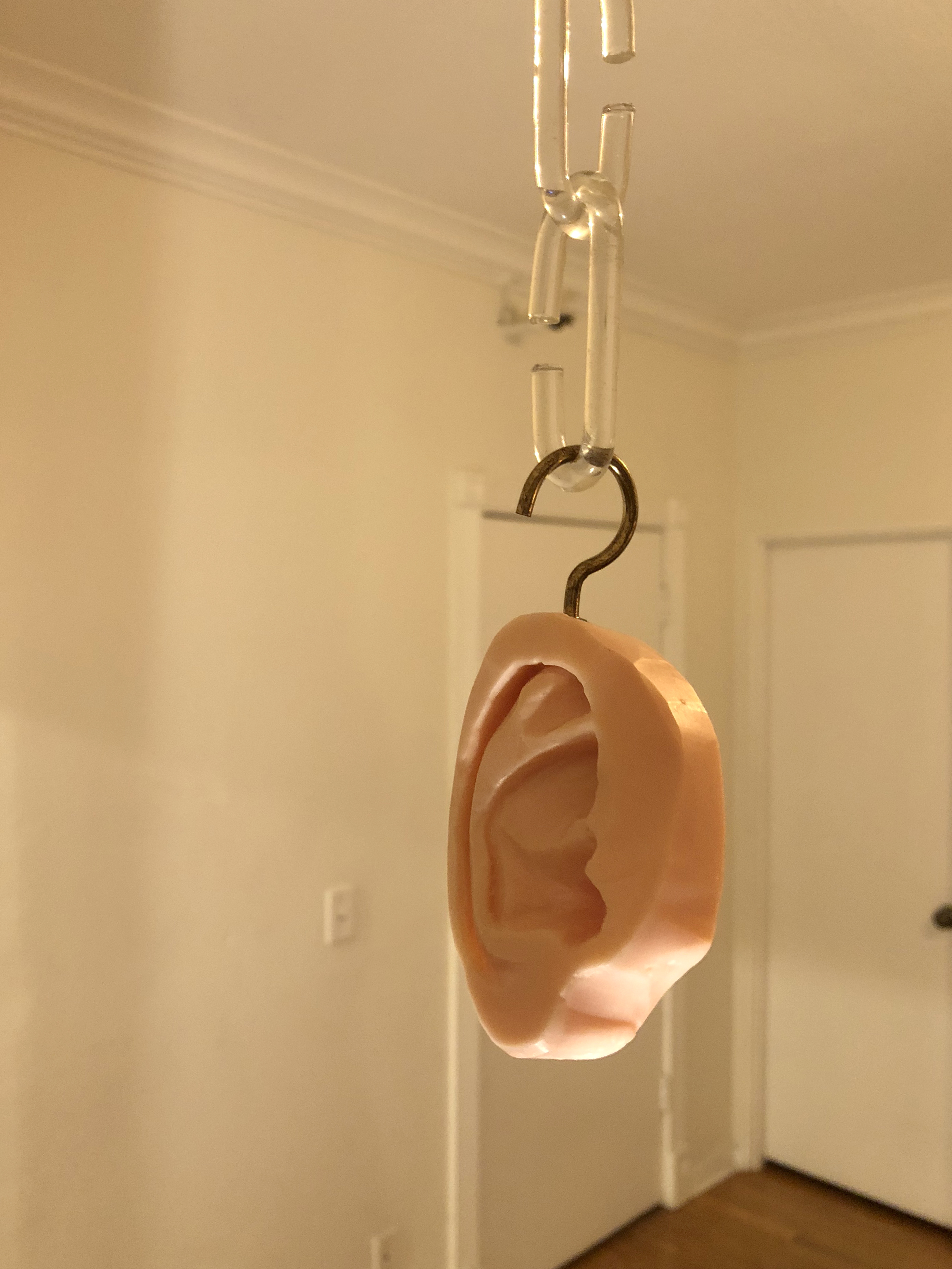 A dove soap bar carved into the shape of an ear hung from the ceiling by plastic chains